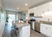 Thumbnail 44 of 80 - A kitchen with white cabinets and a large island at The Barnum Apartments, White Bear Lake, 55110