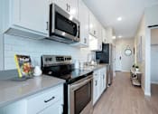 Thumbnail 54 of 80 - A kitchen with white cabinets and a black stove top oven at The Barnum Apartments, Minnesota