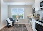 Thumbnail 60 of 80 - A kitchen with a grey chair and a table with a white cloth on it at The Barnum Apartments, White Bear Lake, MN,  55110