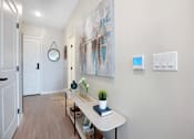 Thumbnail 61 of 80 - A hallway with a white table and a painting on the wall at The Barnum Apartments, White Bear Lake