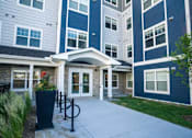 Thumbnail 79 of 80 - A building with a white and blue exterior and a covered walkway entrance at The Barnum Apartments, White Bear Lake, MN,  55110