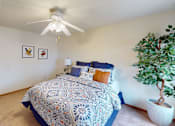 Thumbnail 6 of 12 - A bedroom with a bed, a ceiling fan, and a potted plant.