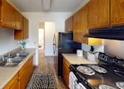 Thumbnail 3 of 12 - A kitchen with wooden cabinets and a black refrigerator.
