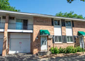 Thumbnail 11 of 12 - A red brick building with a green awning and a white garage door.
