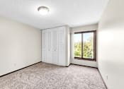 Thumbnail 7 of 28 - A room with a carpeted floor and a window showing greenery outside.