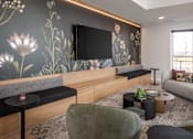 Thumbnail 9 of 92 - A living room with a grey sofa, a black coffee table, a green armchair, and a television mounted on the wall.