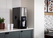 Thumbnail 14 of 92 - A coffee machine is on a counter with two cups labeled "BADI BADI" in front of it.