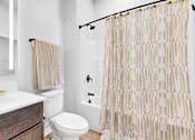 Thumbnail 56 of 92 - A bathroom with a toilet, sink, and shower curtain.