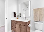 Thumbnail 55 of 92 - A white toilet sits next to a sink with a mirror above it.
