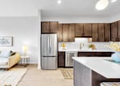 Thumbnail 46 of 92 - A modern kitchen with a refrigerator, sink, and wooden cabinets.