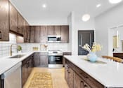 Thumbnail 41 of 92 - A modern kitchen with dark wood cabinets and white countertops.