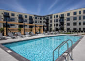 Thumbnail 92 of 92 - A swimming pool in front of a building with lounge chairs around it.