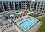 Thumbnail 2 of 92 - A large outdoor swimming pool surrounded by a black fence and a wooden deck with chairs.
