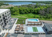 Thumbnail 3 of 92 - A large outdoor swimming pool with a green grassy area and a building in the background.