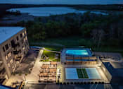 Thumbnail 67 of 92 - A building with a pool and a deck with lights on it.