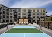 Thumbnail 59 of 92 - A tennis court is located in the courtyard of a modern apartment building.