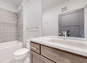 Thumbnail 28 of 64 - A white toilet sits next to a white sink in a modern bathroom.