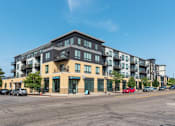 Thumbnail 54 of 64 - A large apartment building with a parking lot in front.