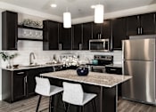 Thumbnail 1 of 81 - A modern kitchen with a granite countertop and stainless steel appliances.