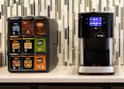 Thumbnail 11 of 81 - A vending machine with a variety of snacks and a coffee machine on a counter.