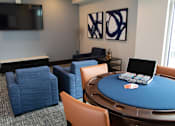 Thumbnail 16 of 81 - A poker table with chairs and a television in the background.