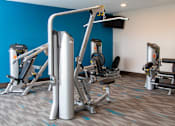 Thumbnail 18 of 81 - A gym with a blue wall and a variety of exercise equipment.
