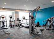 Thumbnail 19 of 81 - A gym with a variety of exercise equipment including treadmills, stationary bikes, and weight machines.