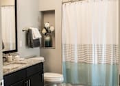 Thumbnail 25 of 81 - A bathroom with a toilet, sink, and shower curtain.