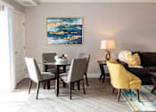 Thumbnail 27 of 81 - A living room with a grey couch, a yellow chair, a grey dining table and chairs, a painting on the wall, and a lamp on the side table.