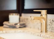Thumbnail 29 of 81 - A bathroom sink with a marble countertop and a gold faucet.