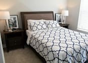 Thumbnail 31 of 81 - A bed with a white and blue patterned comforter sits in a room with two lamps on either side.