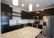 Thumbnail 32 of 81 - A kitchen with black cabinets and a granite countertop.