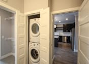 Thumbnail 43 of 81 - A white washing machine is in a small laundry room.