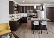 Thumbnail 48 of 81 - A modern kitchen with dark brown cabinets and a yellow chair.