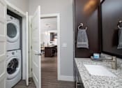 Thumbnail 59 of 81 - A white washing machine is in a small laundry room.
