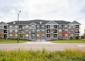 Thumbnail 69 of 81 - A large apartment complex with a grassy area in front.