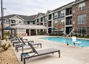 Thumbnail 74 of 81 - A pool area with sun loungers and a slide in front of apartment buildings.