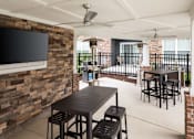 Thumbnail 77 of 81 - A patio with a table and chairs and a television on a brick wall.