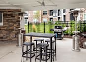 Thumbnail 78 of 81 - A patio with a table and chairs and a grill.