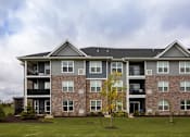 Thumbnail 81 of 81 - A large apartment building with a grassy front yard and a yellow tree.