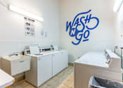 Thumbnail 12 of 20 - A laundromat with a blue wall graphic that says Wash 'n Go.