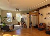 Thumbnail 14 of 20 - A living room with a wooden floor and a ceiling fan.
