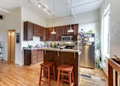 Thumbnail 6 of 20 - A kitchen with wooden floors and a large island with a bar stool.