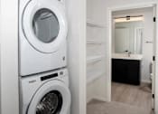 Thumbnail 8 of 47 - A white washing machine and dryer in a small laundry room at The Redwell Apartments, Minnesota 55401