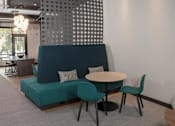Thumbnail 13 of 47 - A modern living room with a green sofa, a round table, and a patterned wall at The Redwell Apartments, Minnesota 55401