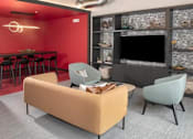 Thumbnail 16 of 47 - A living room with a sofa, two chairs, and a television at The Redwell Apartments, Minnesota