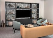 Thumbnail 18 of 47 - A living room with a television, two chairs, and a coffee table at The Redwell Apartments, Minneapolis