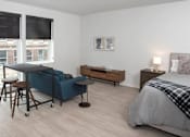 Thumbnail 21 of 47 - A bedroom with a bed, a sofa, a table, and a window at The Redwell Apartments, Minneapolis, MN 55401