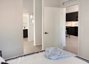Thumbnail 22 of 47 - A bedroom with a bed and a kitchen area in the background at The Redwell Apartments, Minnesota