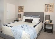 Thumbnail 23 of 47 - A bedroom with a bed, two lamps, a nightstand, and two wall art pieces at The Redwell Apartments, Minneapolis, MN